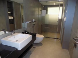 Un baño moderno con un espejo grande, lavamanos blanco y retrete.