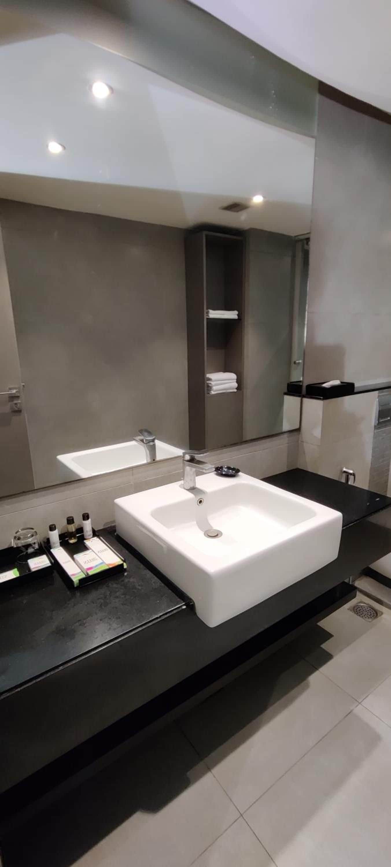 A modern bathroom with a large white sink, a mirror, and a black countertop.