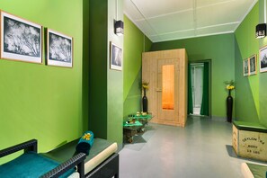 A room with green walls, framed pictures, a wooden door, a small table with items, and a wicker chair. - Scottish Planter Glendevon Bungalow (Walapane)