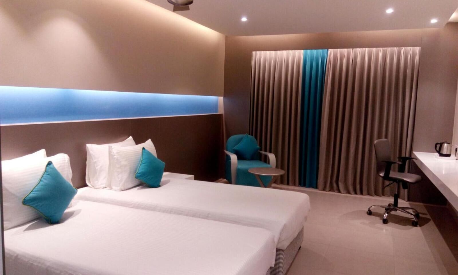 Una habitación de hotel con dos camas, un escritorio, una silla y una mesita.