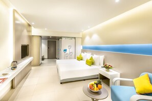 A modern hotel room with a large bed, bedside table, and a small round table with fruit. - ZIBE Coimbatore by GRT Hotels (Coimbatore)