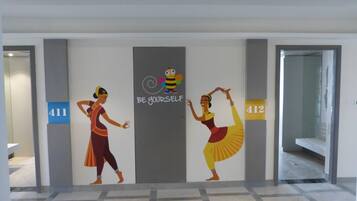Una pared con dos figuras bailando, una ilustración de abeja y el texto "BE YOURSELF".