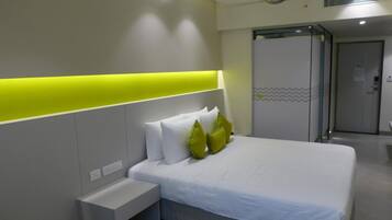 A modern hotel room with a bed, a bedside table, and a bright accent wall.