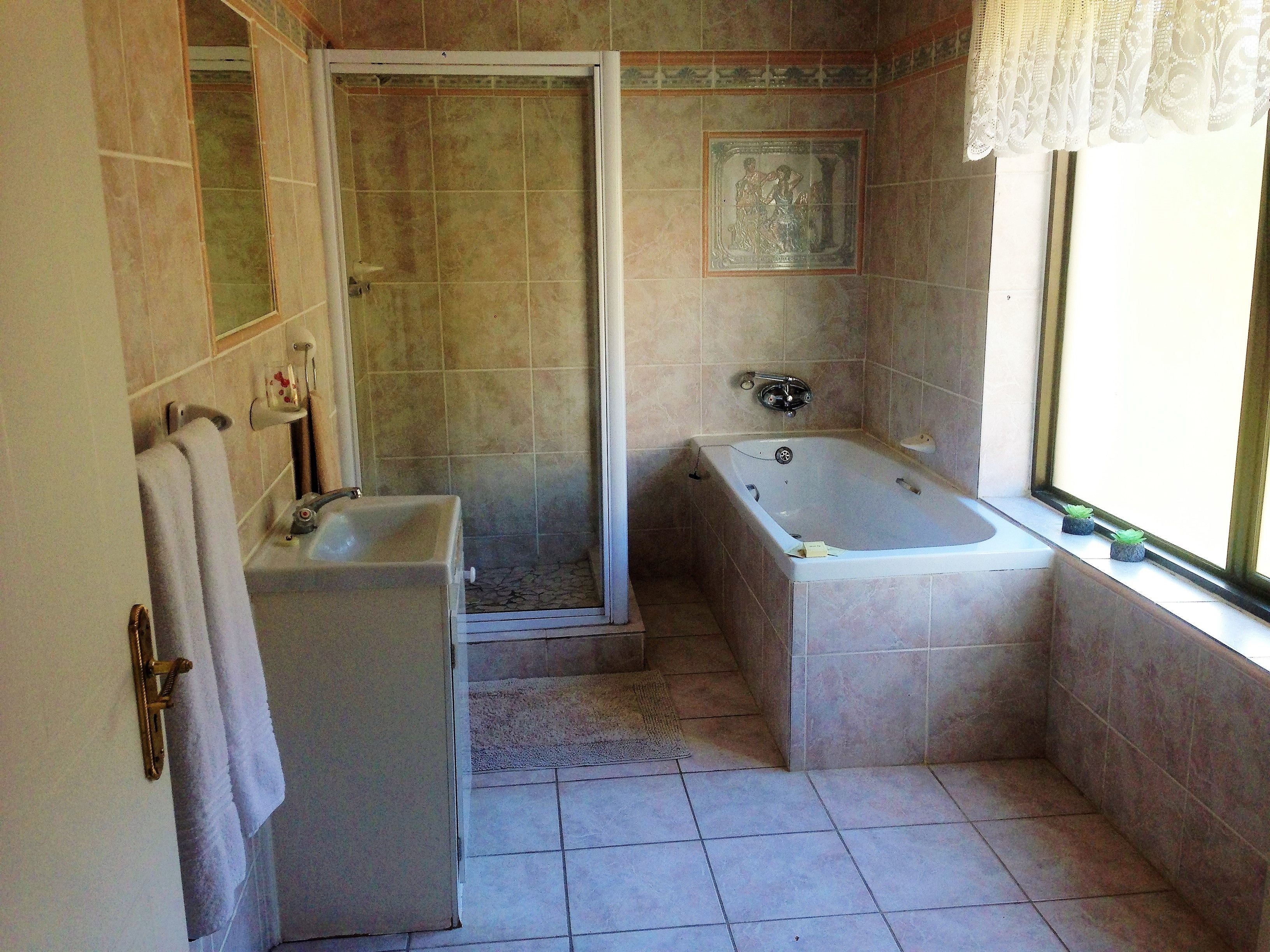 Une salle de bain avec une douche, un lavabo, une baignoire et une fenêtre.