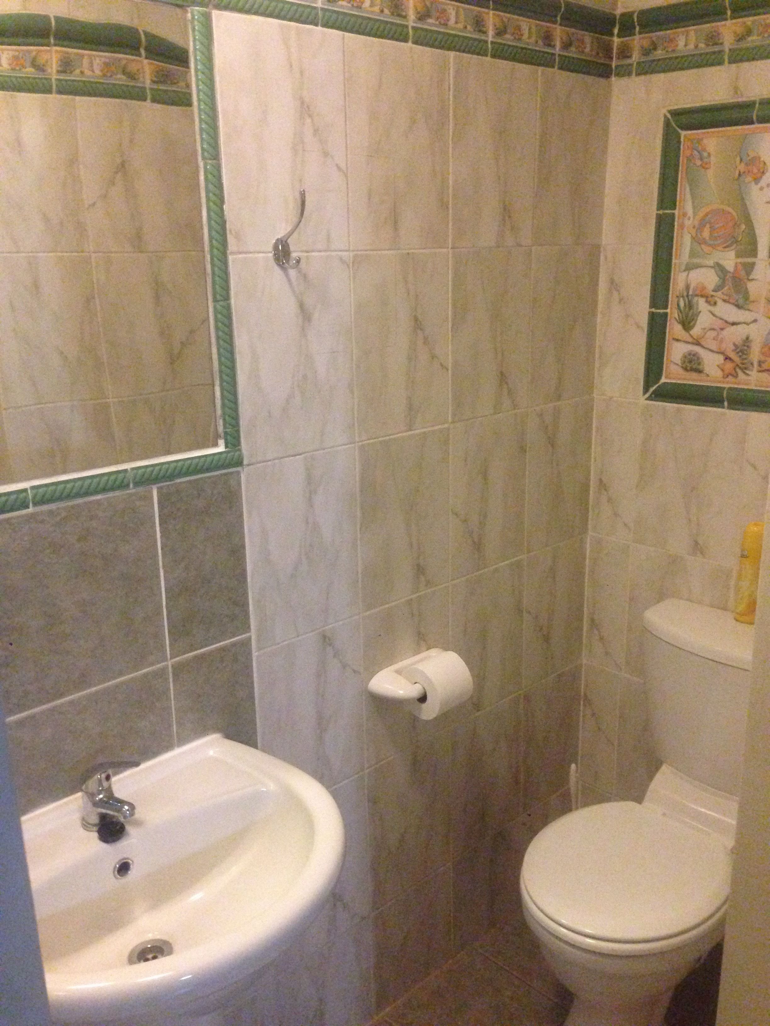 Casa de banho com lavatório, sanita e zona de duche.