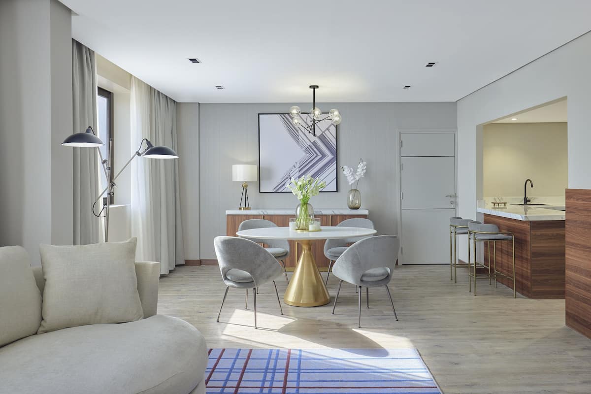 Un salon moderne avec un canapé, une table ronde et deux tabourets de bar.