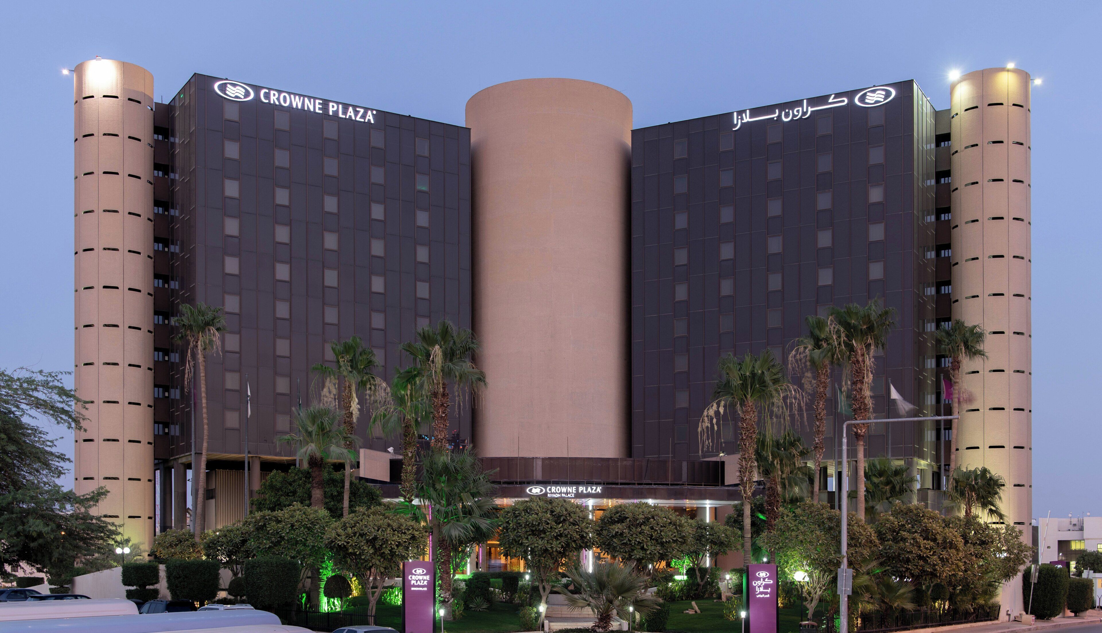 Un hotel con una torre cilíndrica central, varios pisos y una fachada plana con señalización.