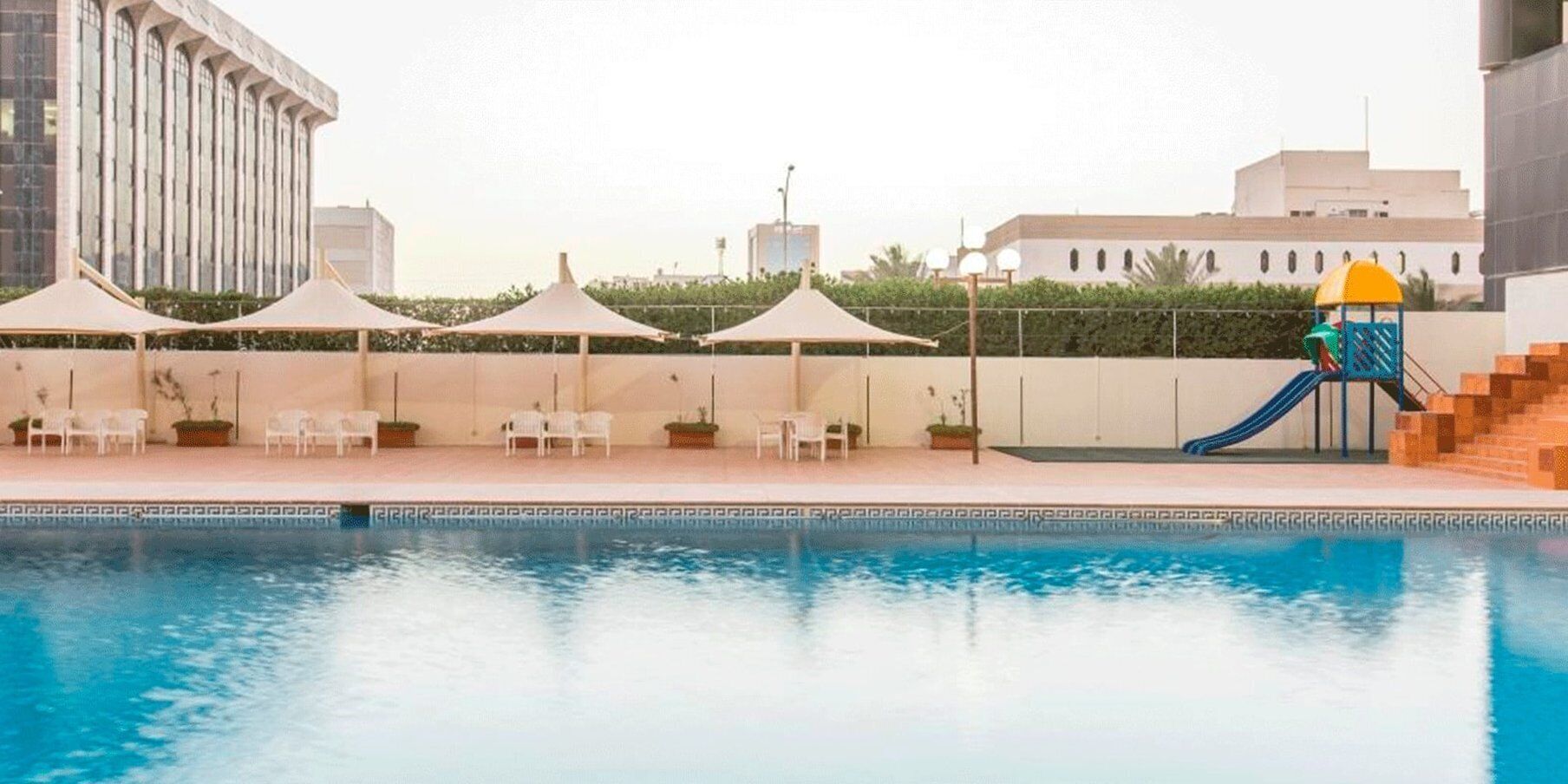 A swimming pool with a slide, lounge chairs, and umbrellas.