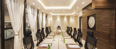 A conference room with a long table, chairs, a clock, and a ceiling light.