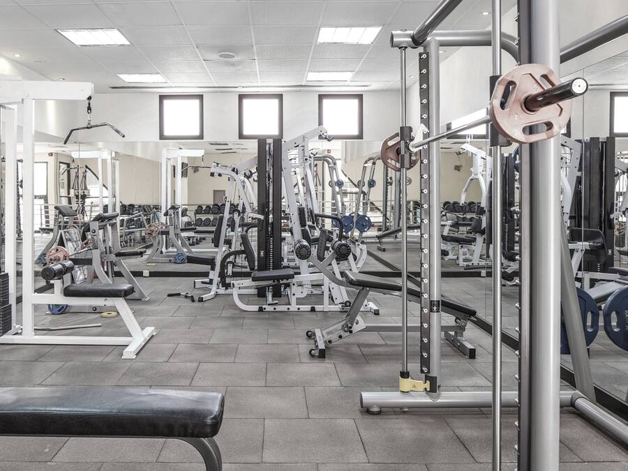 A gym with various exercise equipment, including weight machines, benches, and free weights.