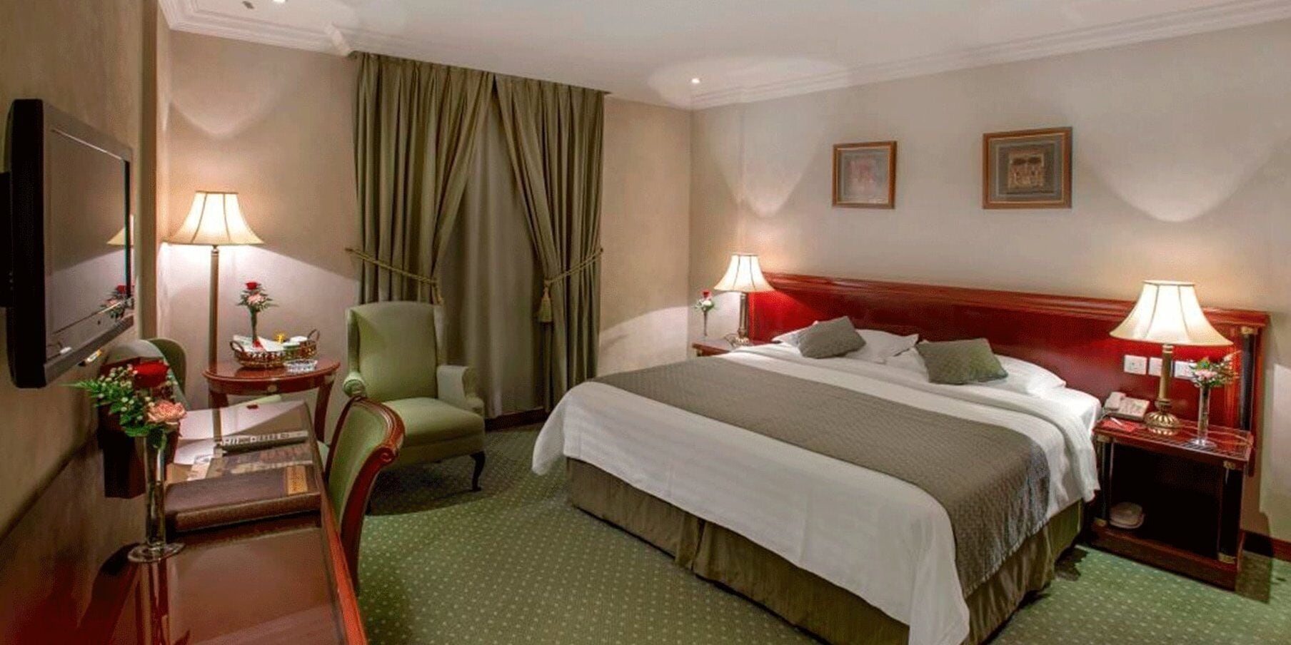 Ett hotellrum med en säng, två sängbord, en stol, ett skrivbord, en lampa, en spegel och ett fönster med gardiner.
