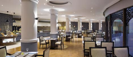 A spacious restaurant with high ceilings, ornate columns, and a variety of seating arrangements.