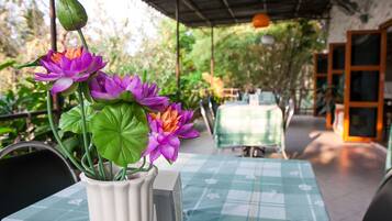A table with a checkered tablecloth, a white vase with purple flowers, and a green plant.