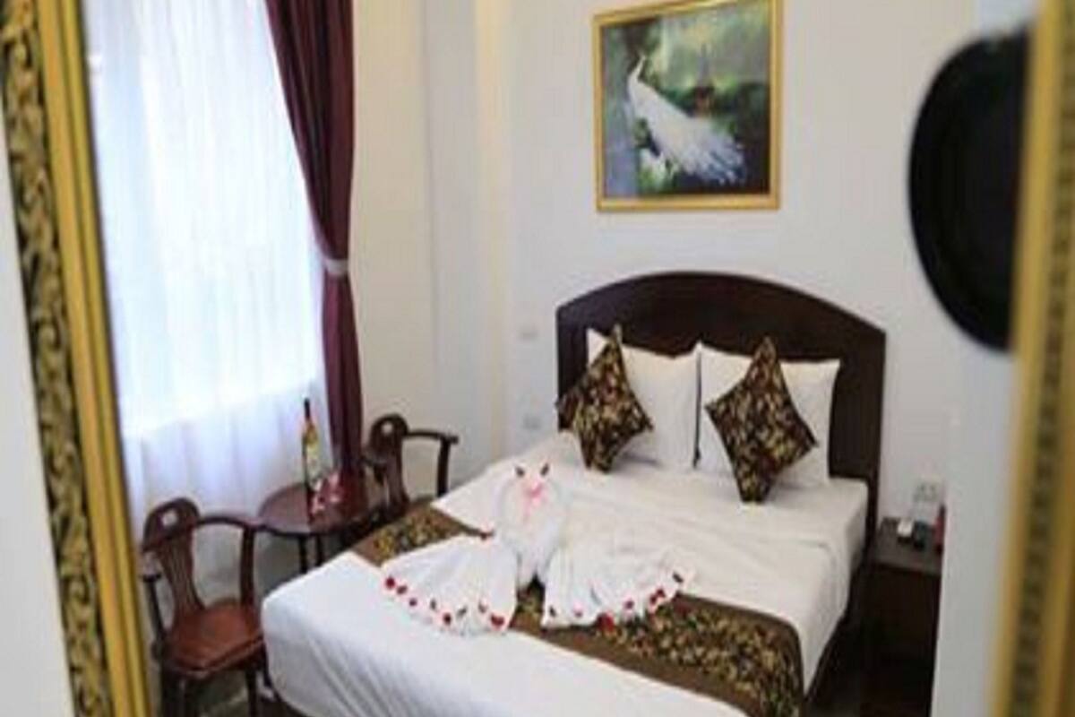 Una habitación de hotel con una cama bien hecha, un cuadro en la pared y una silla.