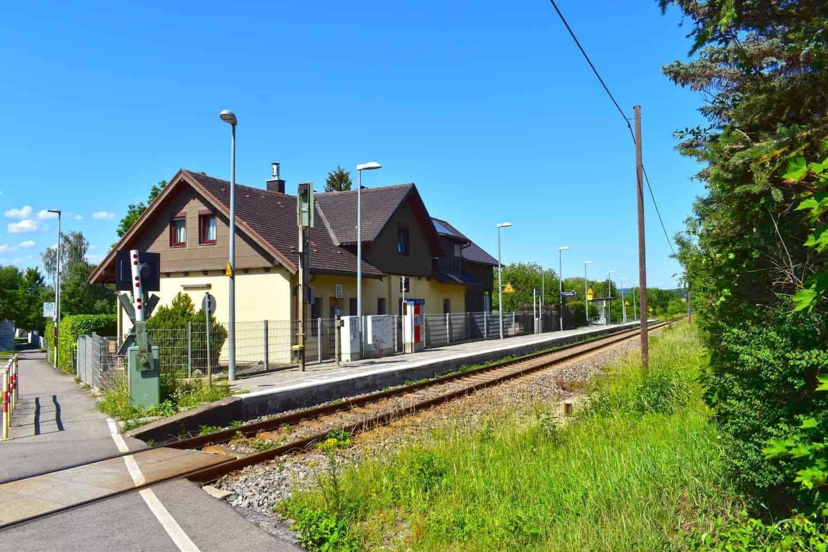 A small train station with a single platform and a building with a sloped roof.