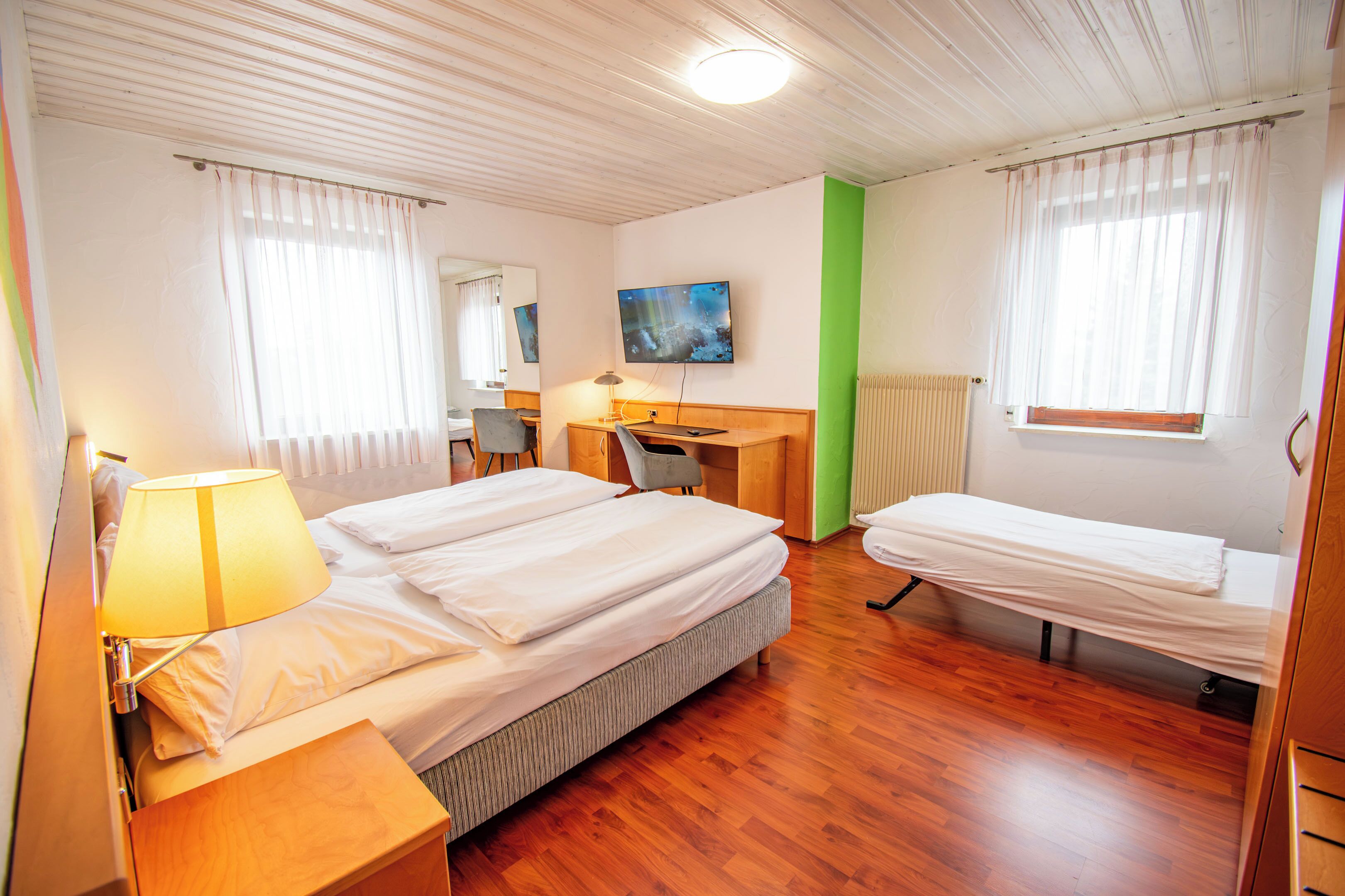 Een hotelkamer met een bed, een bureau, een stoel, een televisie en een raam met gordijnen.