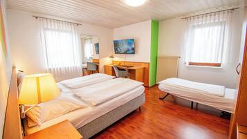 Een hotelkamer met een bed, een bureau, een stoel, een televisie en een raam met gordijnen.