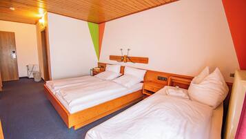Une chambre d’hôtel avec deux lits, des têtes de lit en bois, un plafond en bois et un mur sobre.