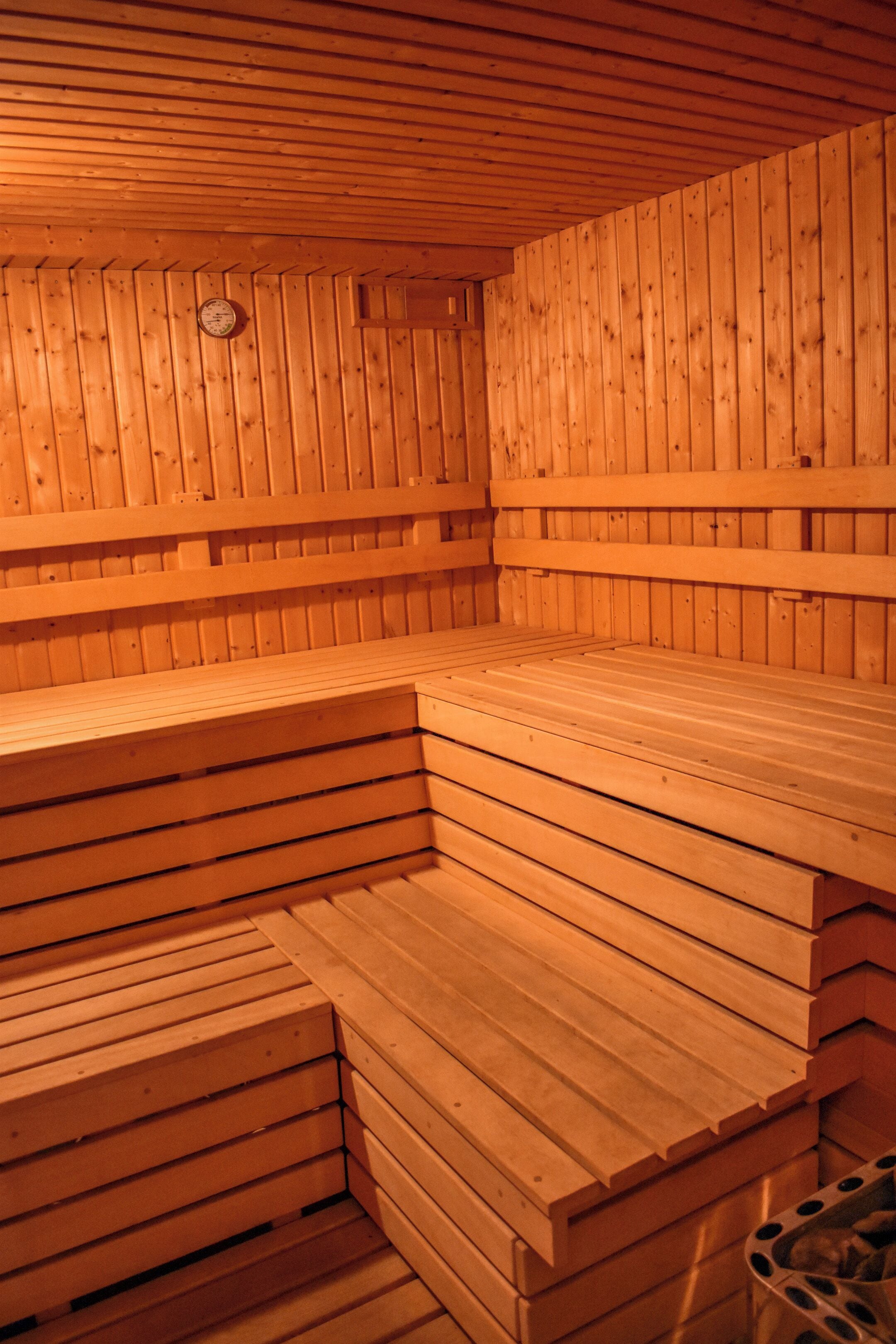 A sauna with wooden benches and a wall-mounted clock.