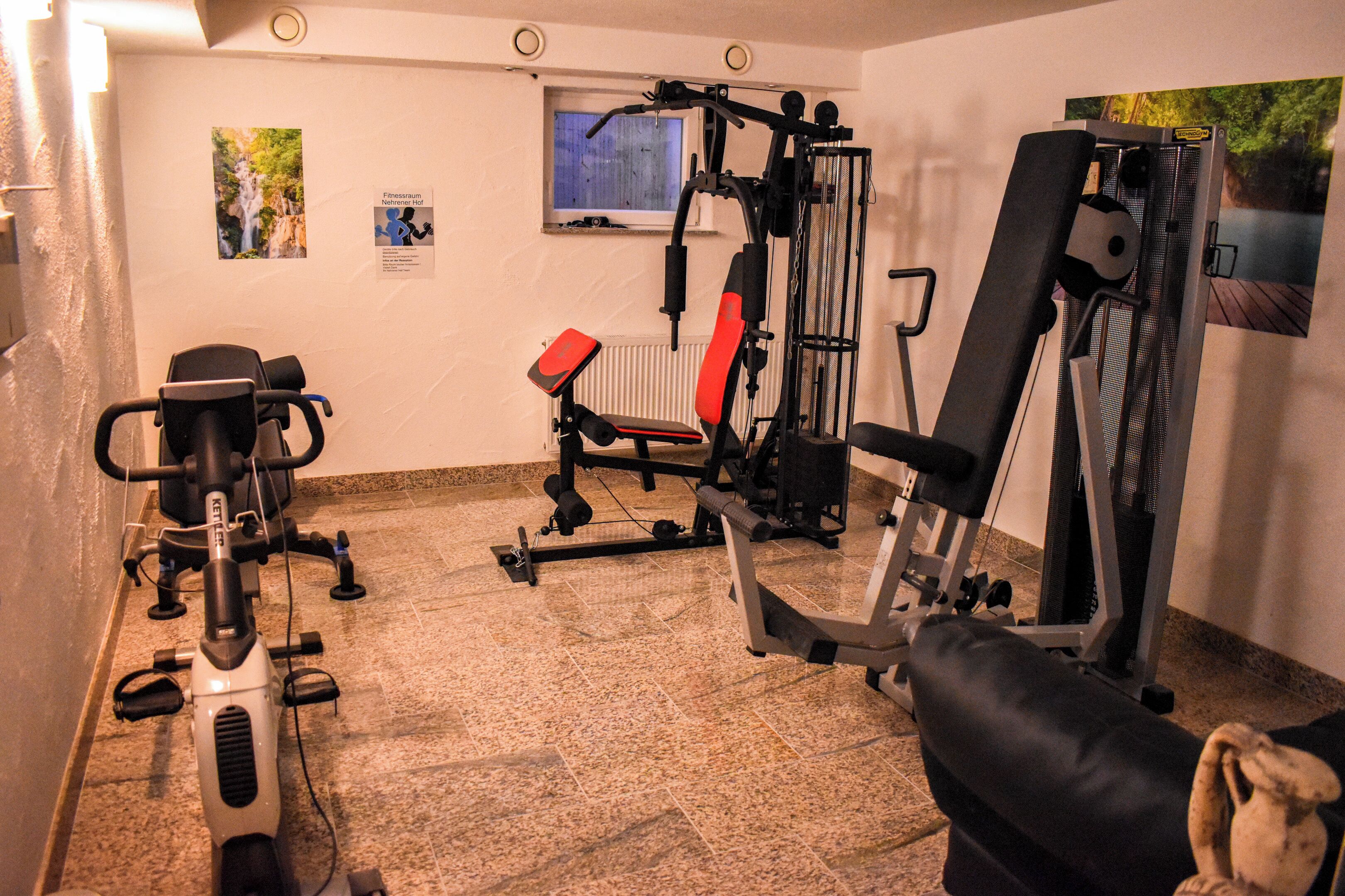 A gym with various exercise machines, a window, and a poster on the wall.