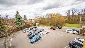Een parkeerplaats met meerdere auto's, bomen en een gebouw op de achtergrond.
