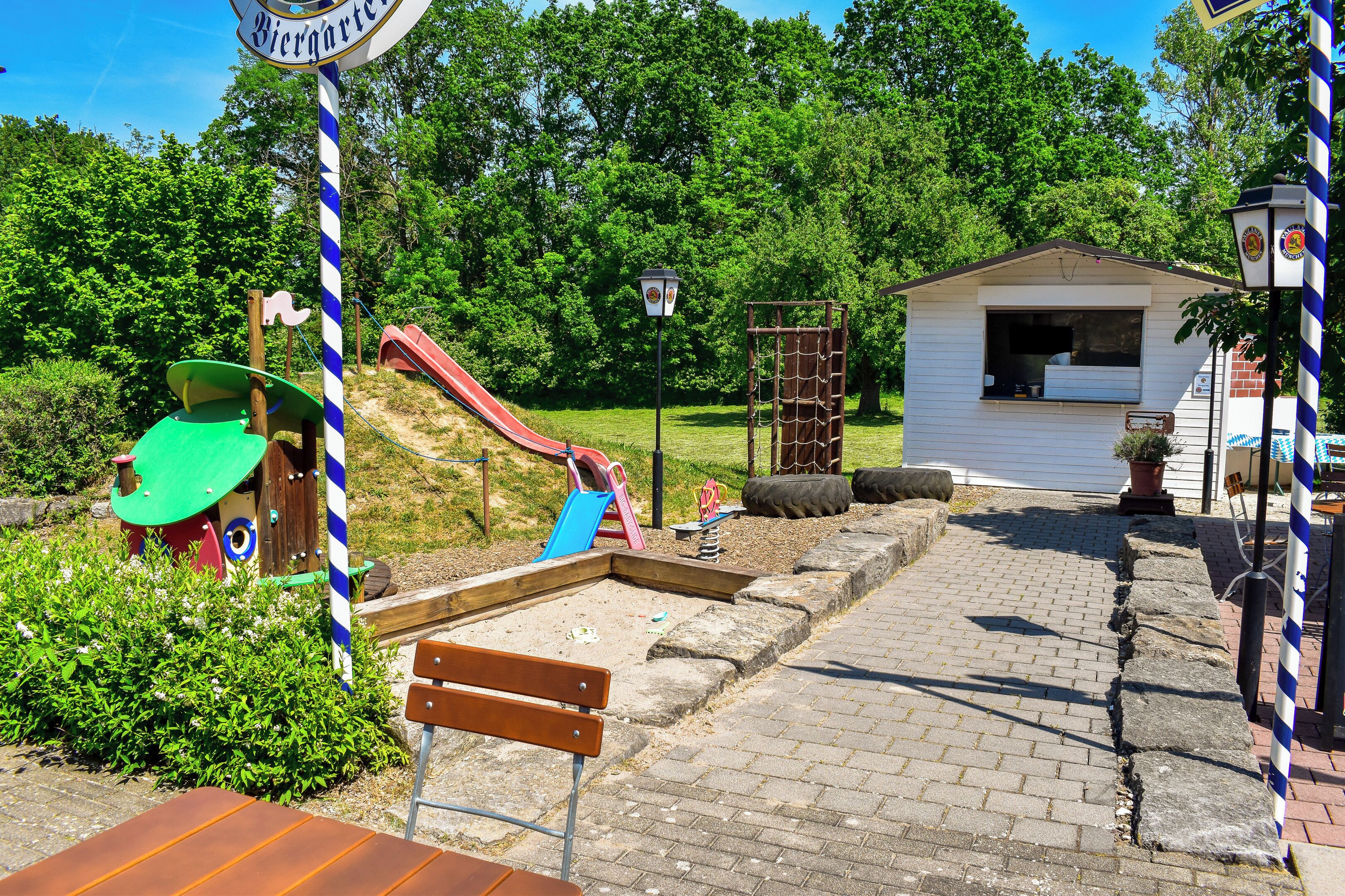 A playground with a slide, a small building, and a bench.