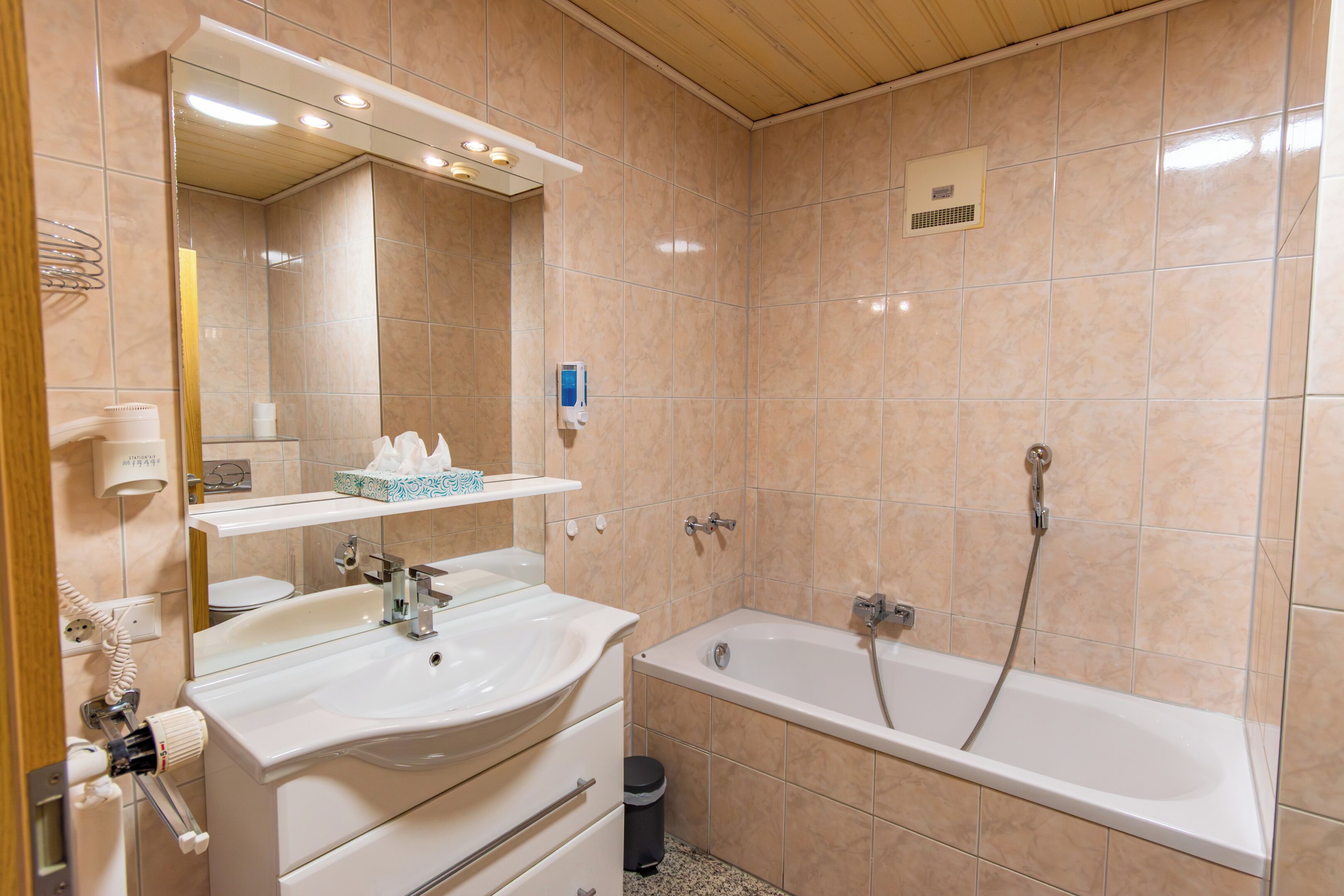 Un baño con lavamanos, espejo, tocador y bañera.