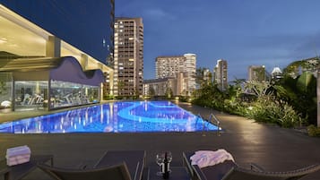 Een buitenzwembad, ligstoelen bij het zwembad