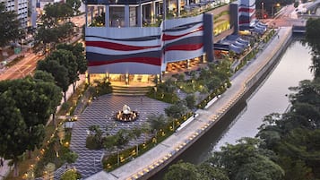 A modern building with a unique wave-patterned facade, a central plaza with a fountain, and a waterfront promenade.