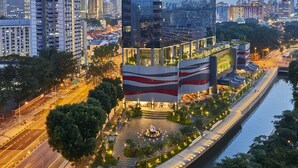 A modern hotel with a glass facade, a rooftop garden, and a riverside location. - Hotel Boss (Singapore)