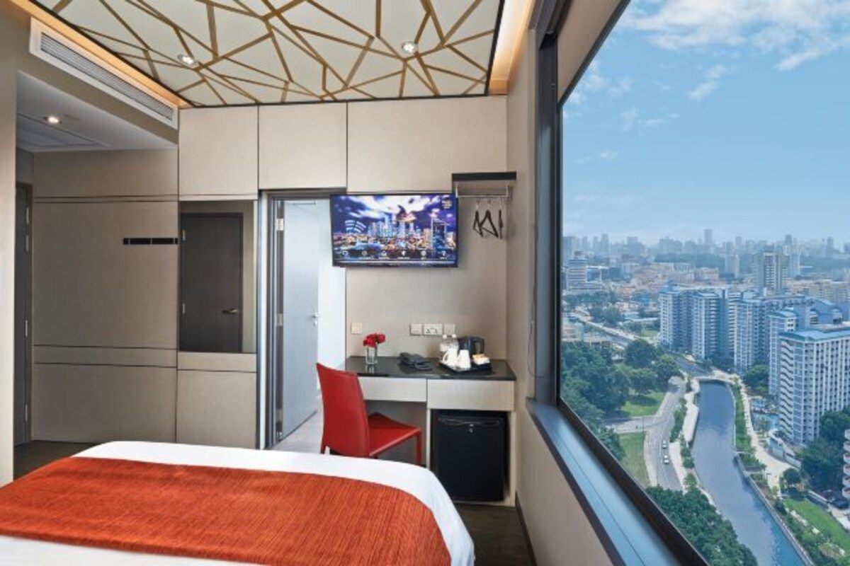 A hotel room with a bed, a desk, a TV, and a city view.