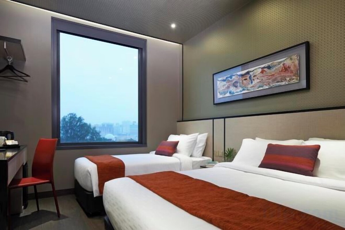 A hotel room with two beds, a desk, a chair, and a large window.