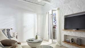 En moderne stue med sofa, to runde sofaborde, et fladskærms-tv på en struktureret væg og en bogreol.