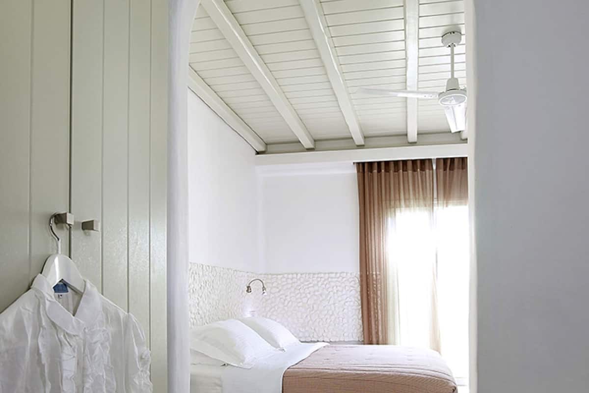 A bedroom with a bed, a hanging robe, and a window with curtains.