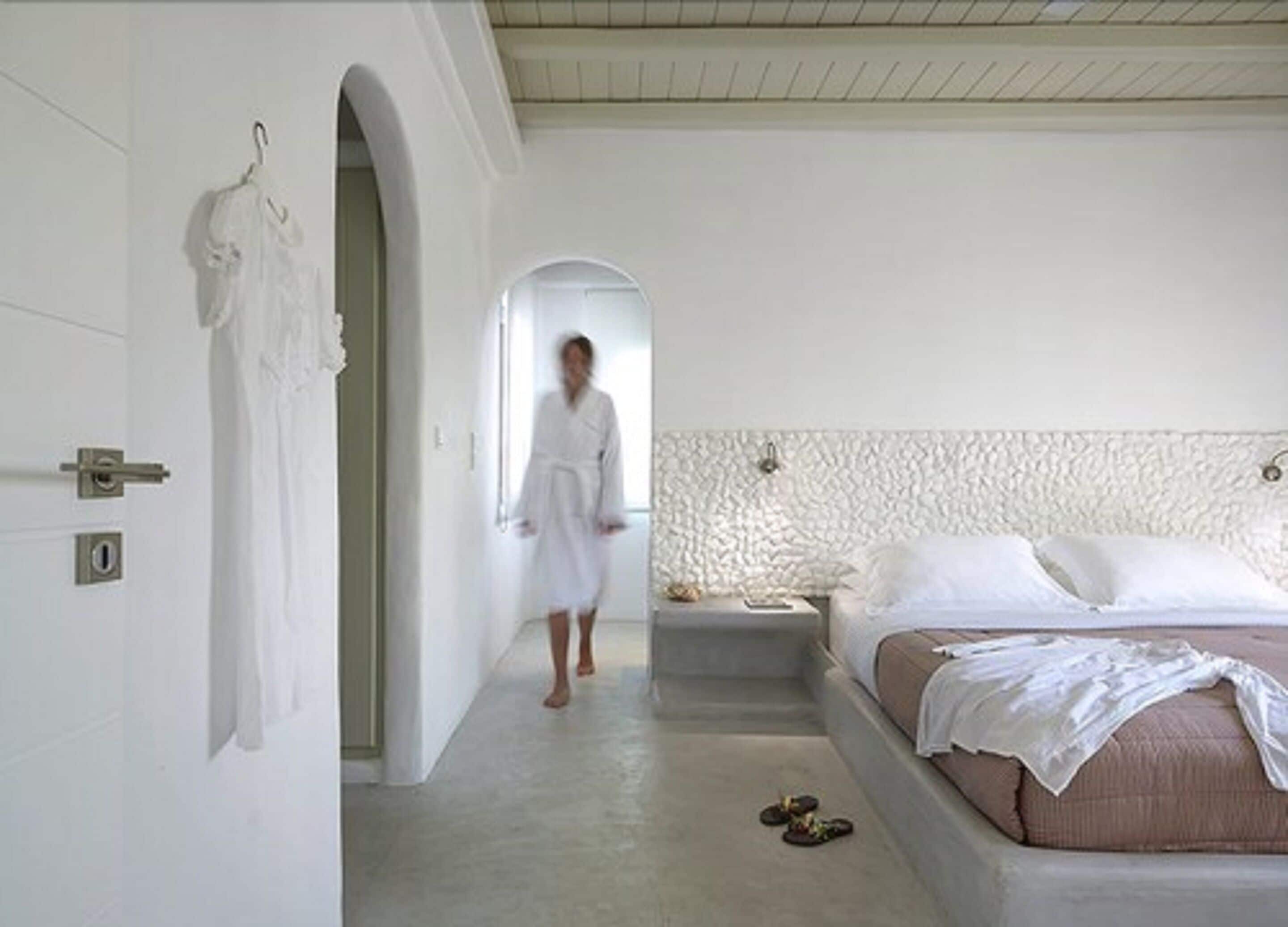 A bedroom with a bed, a nightstand, and a door with a robe hanging on it.