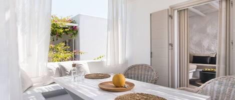 A bright, airy room with a white table, wicker chairs, and a woven placemat.