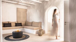 En moderne stue med en beige hjørnesofa, et rundt sort sofabord og to vævede kurve.