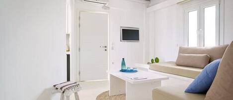A modern living room with a white sofa, a coffee table, and a television mounted on the wall.