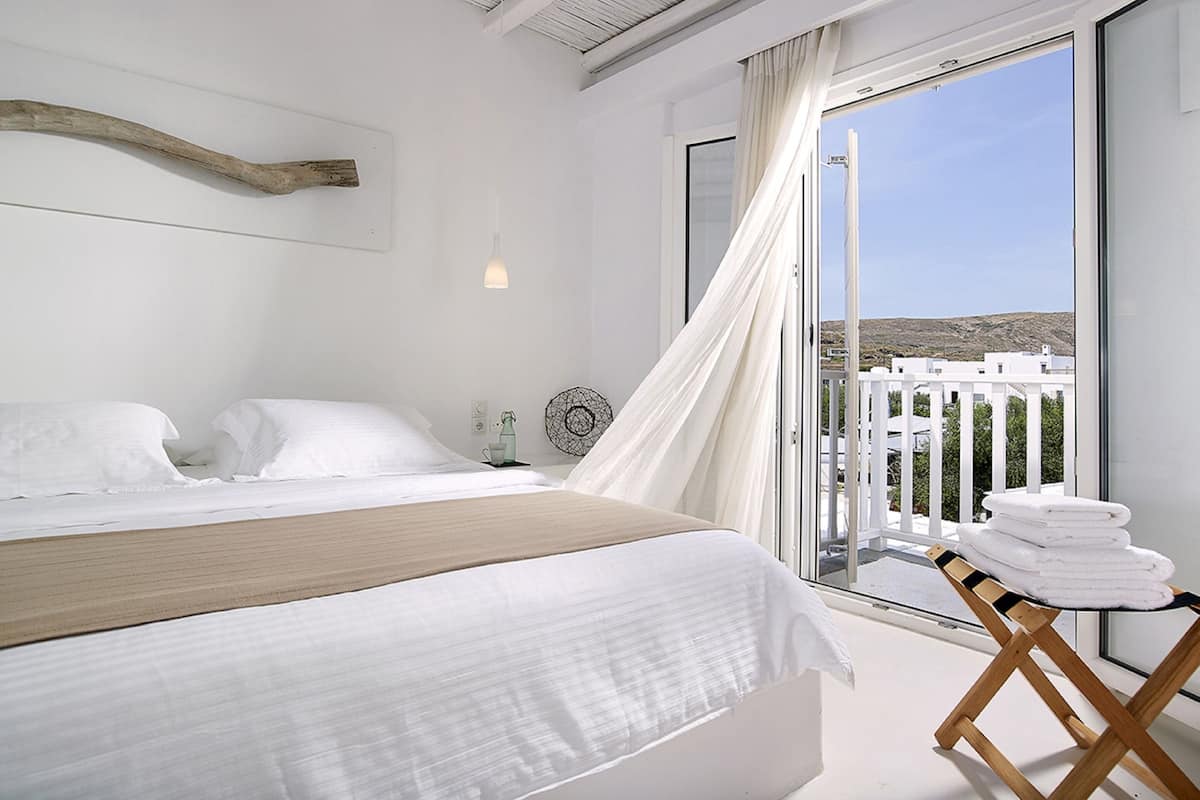 A bedroom with a large bed, a view of the sea, and a balcony with towels.
