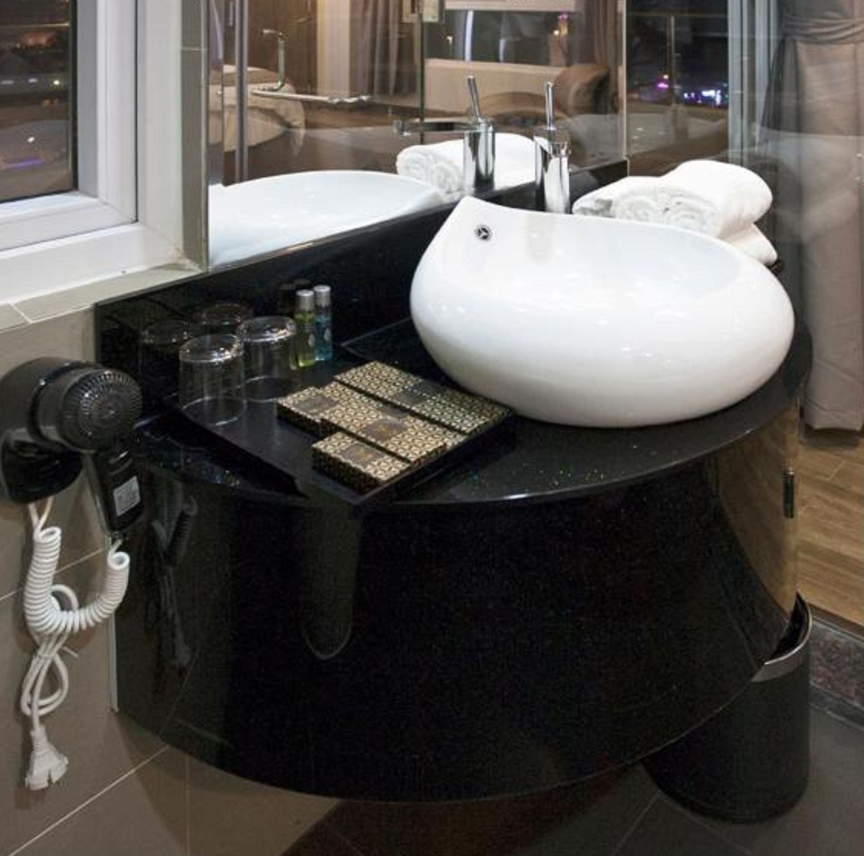 Un baño moderno con un lavamanos grande blanco, un secador de pelo y un espejo.