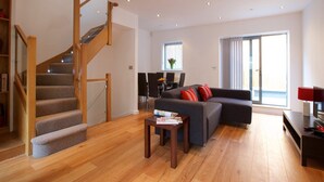 Un salon moderne avec un escalier, un canapé, une table basse et un coin repas.