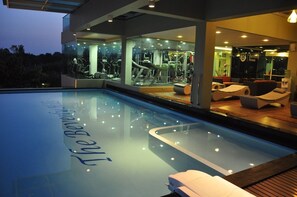 Una piscina al aire libre, sillones reclinables de piscina