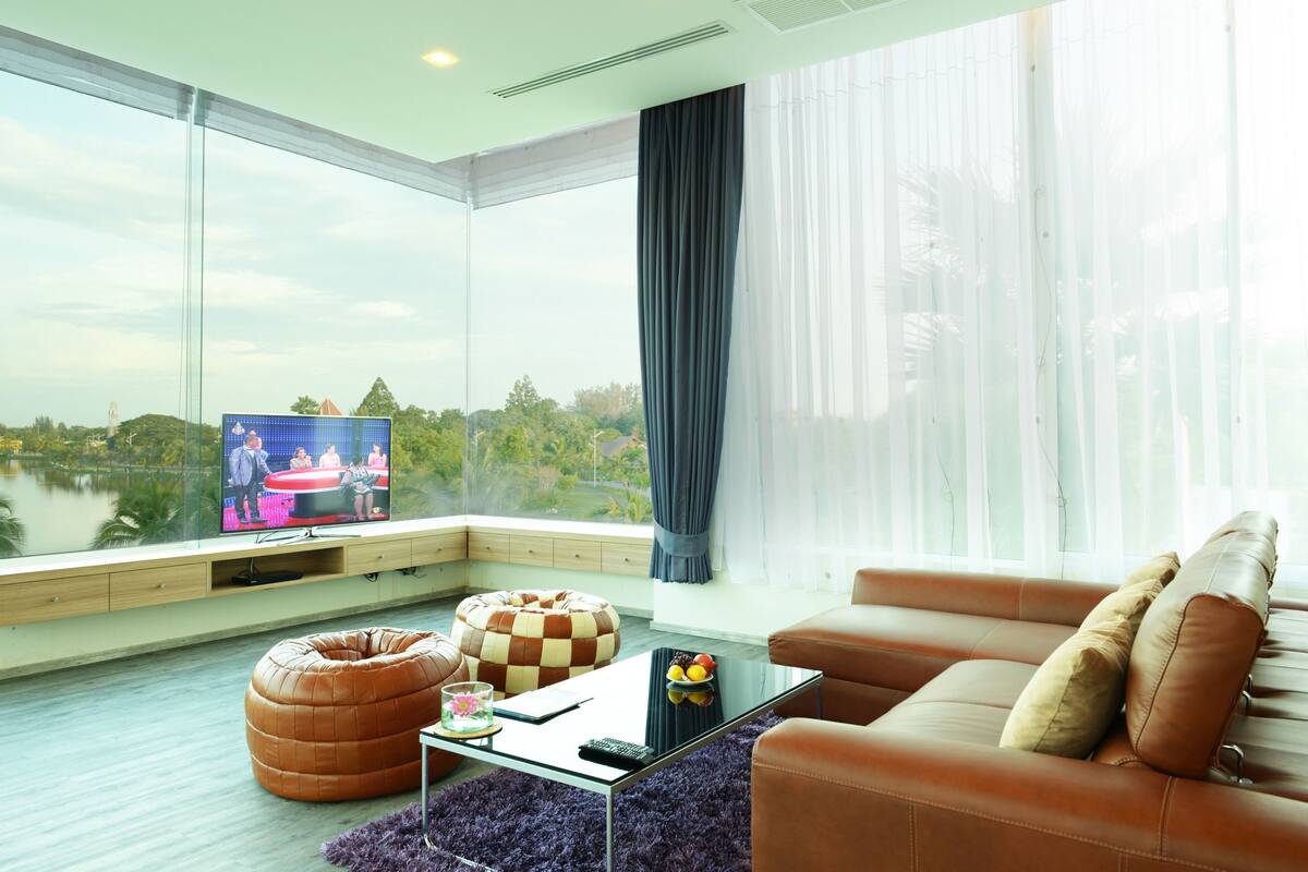 A modern living room with a large TV, leather sofa, and a bean bag chair.