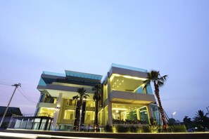 A modern two-story building with a glass facade, palm trees, and a balcony. - The Beverly Hills (Nakhon Ratchasima)
