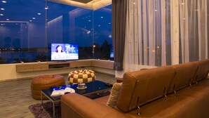Un salon moderne avec une grande fenêtre, un téléviseur, un canapé et une table basse.