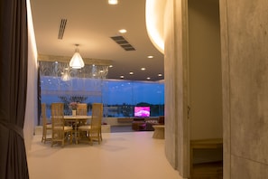A modern living room with a dining area, large windows, and a TV. - The Beverly Hills (Nakhon Ratchasima)