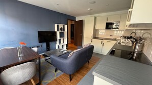 A modern living room with a sofa, a dining table, and a TV.