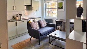 A modern living room with a grey sofa, a coffee table, and a patterned rug.