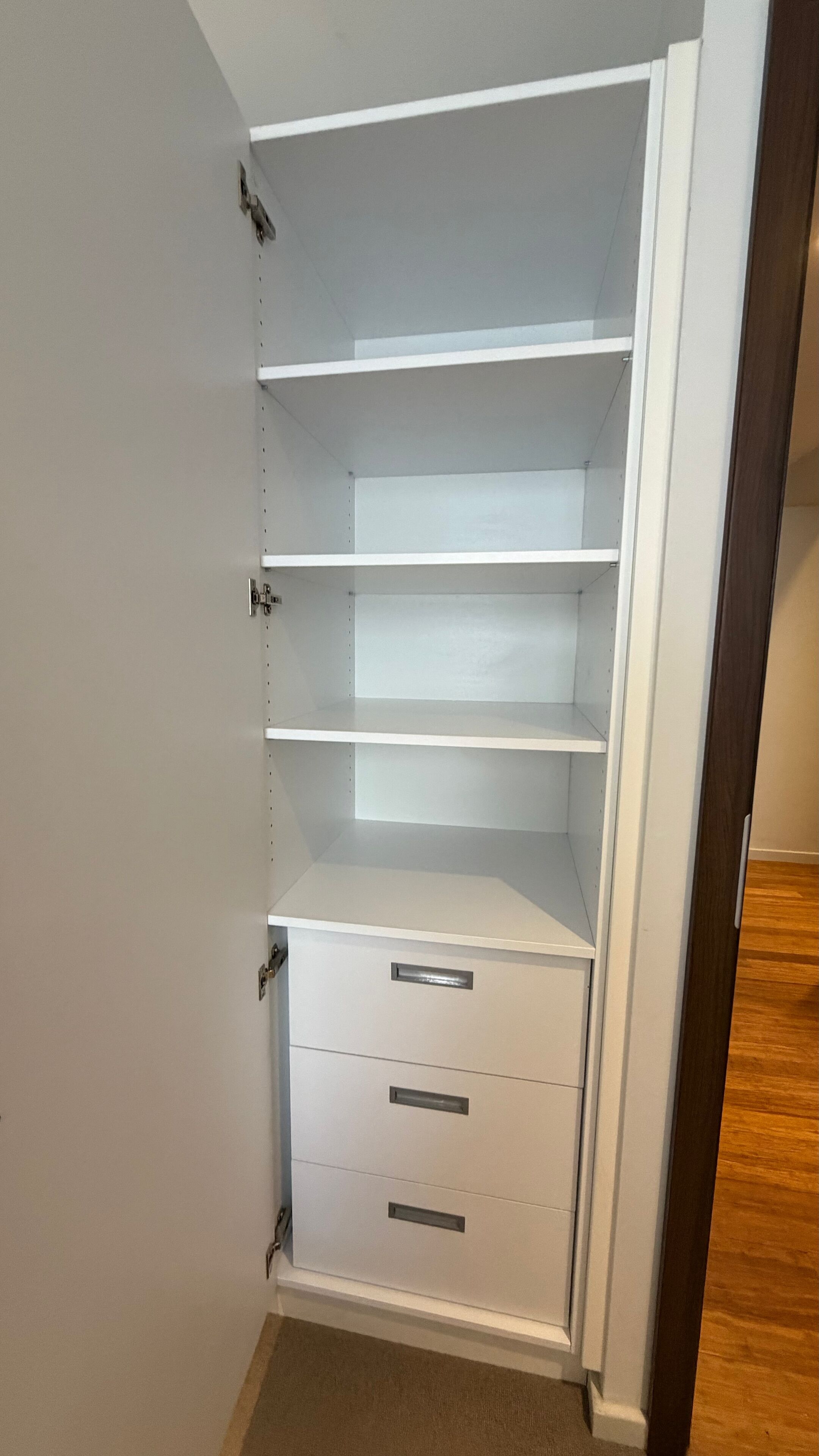 A walk-in closet with open shelving and a set of drawers.