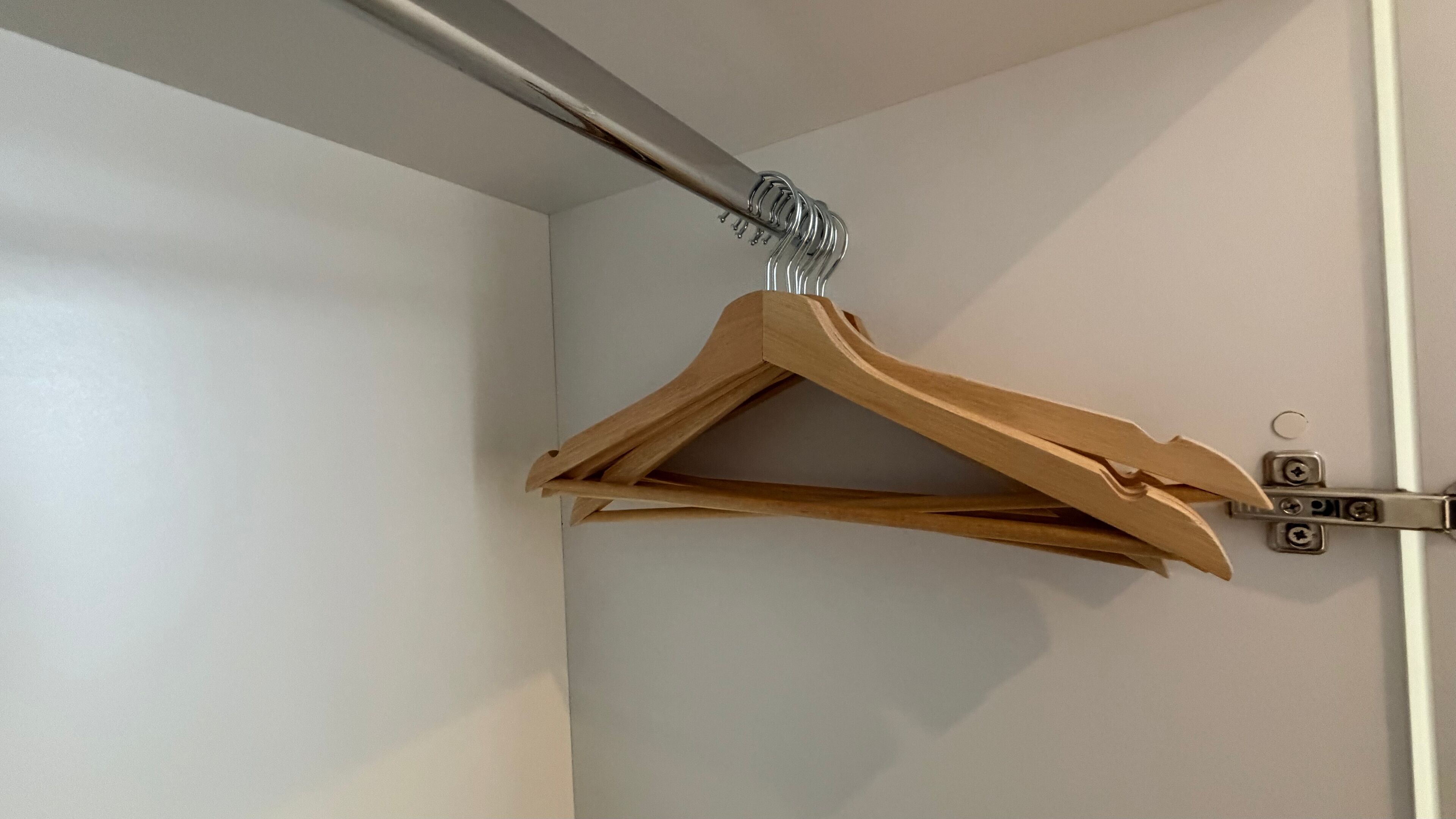 A wooden hanger on a wall-mounted metal bracket.
